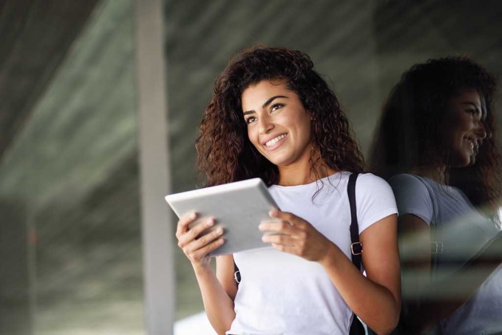 Smiling Arab girl using digital tablet in business background.